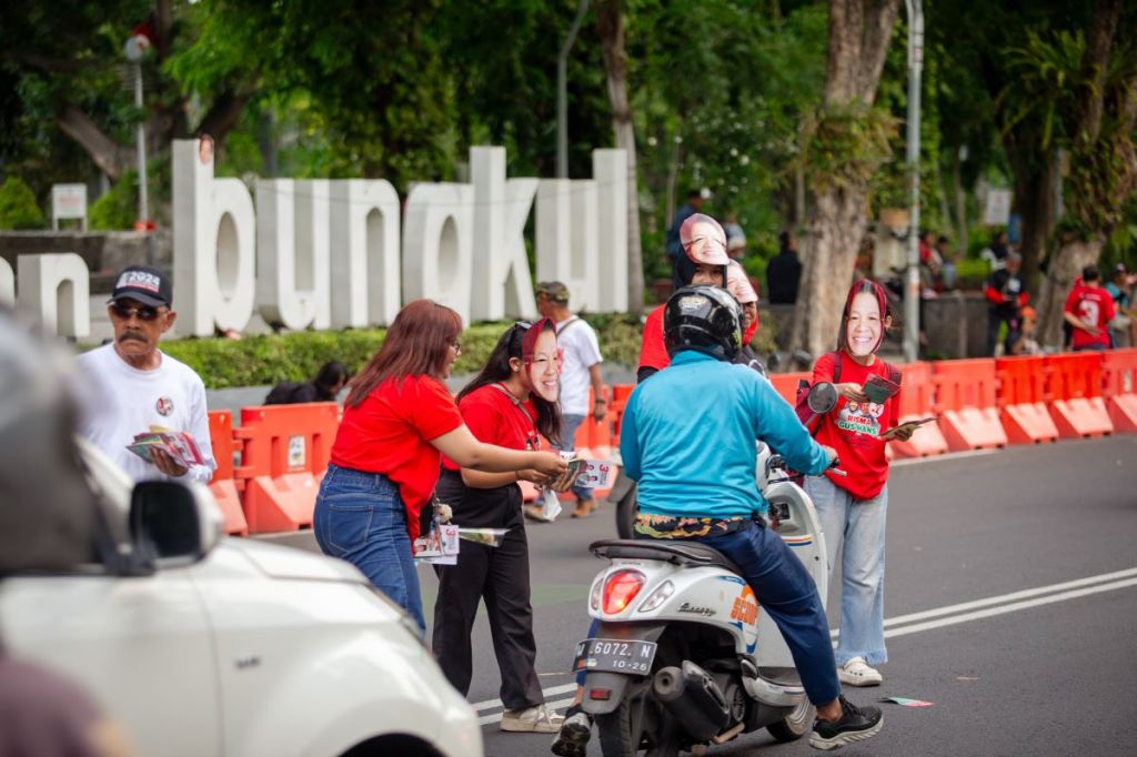 Pakai Topeng Risma, Relawan JAKA Kampanye Simpatik Bagi Brosur dan Bunga