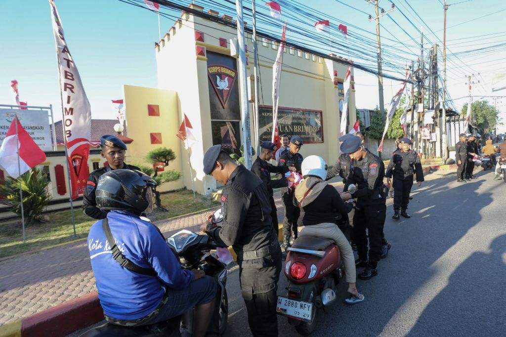 Sambut HUT RI ke-80, Brimob Polda Jatim Bagikan Bendera Merah Putih pada Pengendara